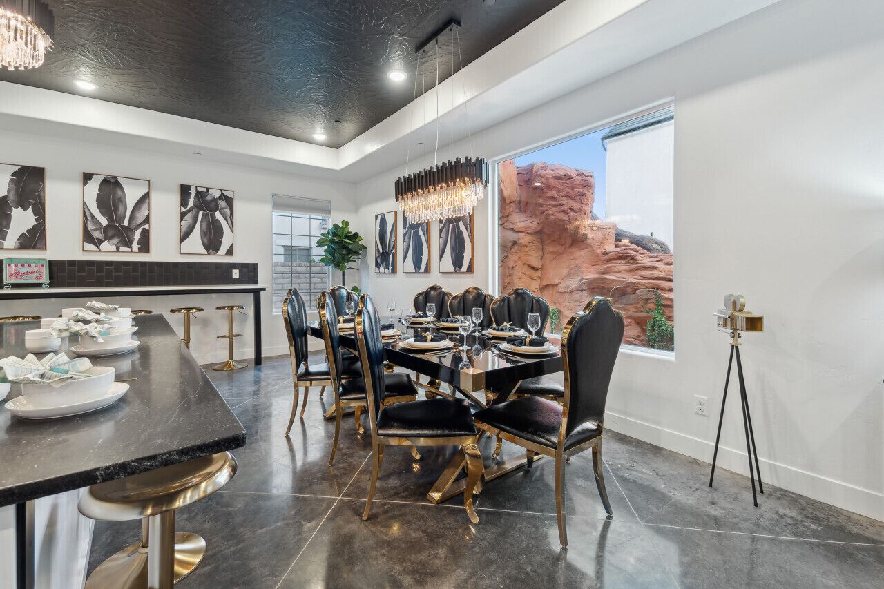 A modern dining area with a black marble table, gold chairs, and a chandelier.