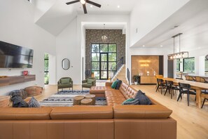 A spacious living area with a large leather sofa, a dining table, and a staircase leading to an upper level.