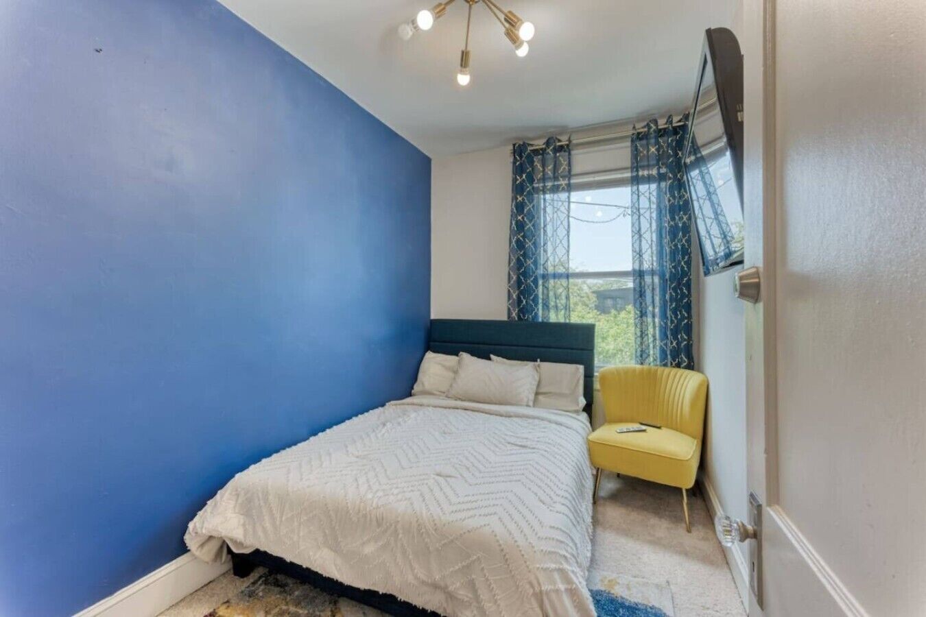 Une chambre à coucher avec un lit, une chaise et une fenêtre avec des rideaux.