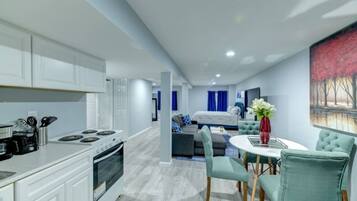 A modern kitchen with white cabinets and a dining area with teal chairs and a white table.