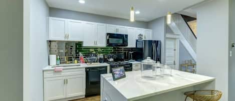 Una cocina moderna con armarios blancos, una isla central y un microondas.
