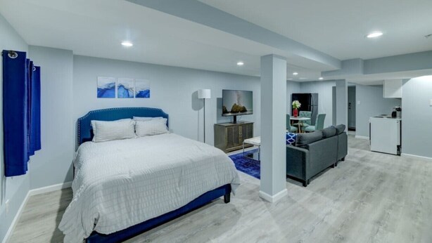 Habitación de hotel moderna con una cama grande, televisión, sofá y kitchenette.
