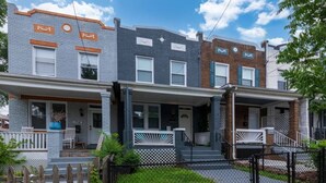 Un hilera de casas de pueblo con porches delanteros, una valla de piquete y un césped bien cuidado.