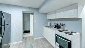 Una cocina moderna con armarios blancos, un refrigerador de acero inoxidable, una estufa y un microondas.