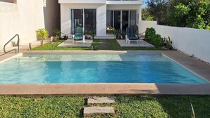 A modern multi-story building with a swimming pool in front. - 3. Vista al mar turquesa. (Progreso)
