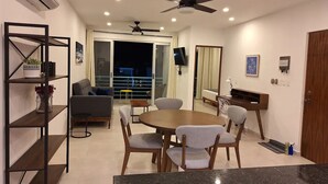 A modern living room with a round table and chairs, a sofa, a TV, and a balcony with a view. - 3. Vista al mar turquesa. (Progreso)