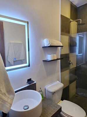Une salle de bain moderne avec un grand lavabo, des toilettes et une douche à parois de verre.