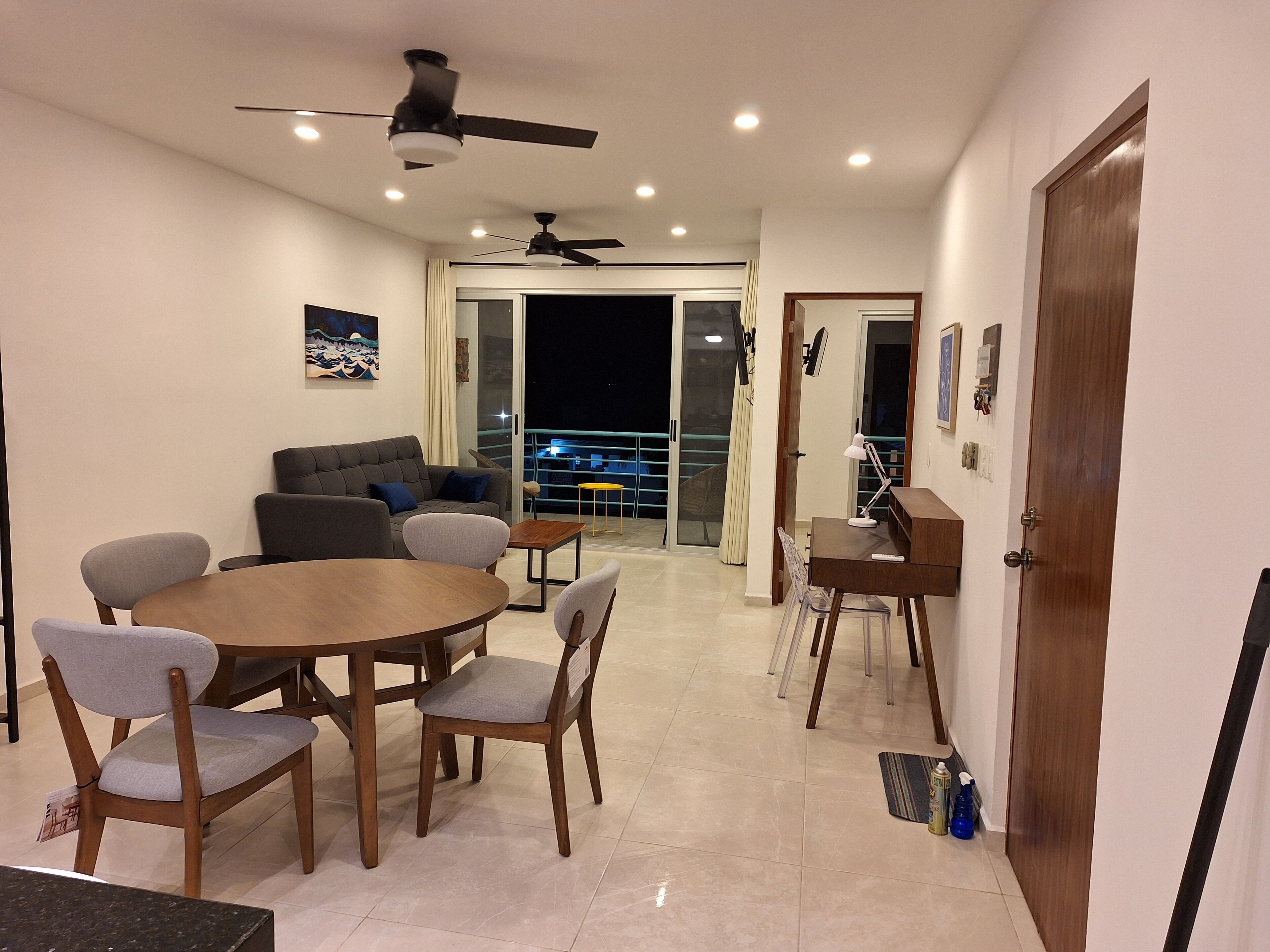A modern living room with a round dining table, two sofas, and a balcony with a railing.
