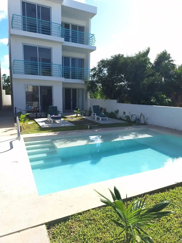 Un bâtiment moderne à deux étages doté d’une piscine, d’un espace extérieur aménagé et d’un jardin bien entretenu.