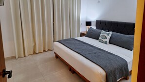 A bedroom with a bed, curtains, a bedside lamp, and a door. - 3. Vista al mar turquesa. (Progreso)
