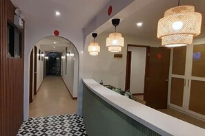 A hotel corridor with a reception desk, patterned floor, and hanging lamps. - Aurora Suites Pasay near Airport (Pasay)