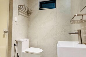 A bathroom with a toilet, a sink, and a shower area. - Aurora Suites Pasay near Airport (Pasay)