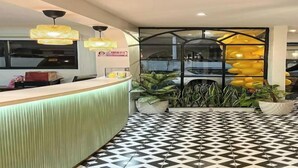 A reception area with a green counter, black and white patterned floor, and hanging yellow lights. - Aurora Suites Pasay near Airport (Pasay)