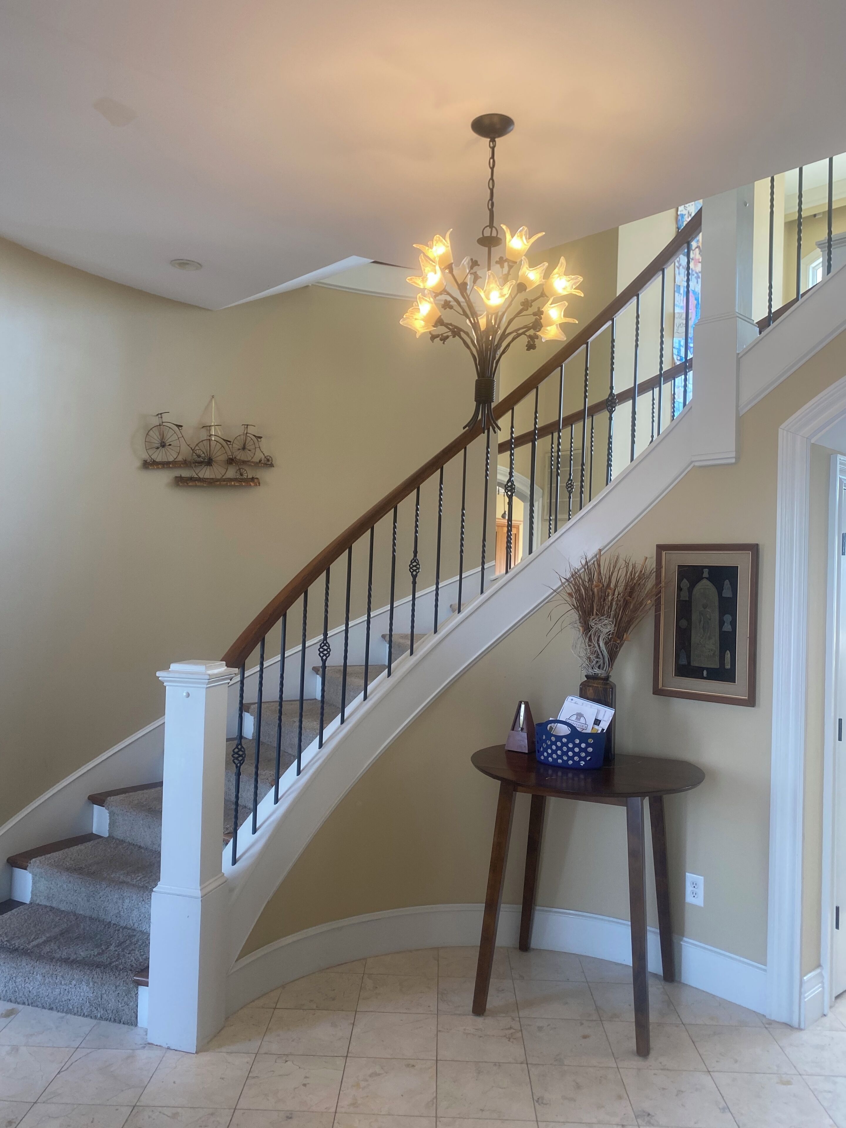 A staircase with a wooden handrail and a chandelier.