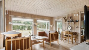 A cozy cabin interior with wooden walls and floors, a dining area with a table and chairs, and a seating area with a sofa and armchairs. - 2 bedroom beautiful home in Hals (Hals)