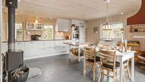 A modern kitchen with white cabinets, a central island, and a wood-burning stove. - 2 bedroom beautiful home in Hals (Hals)