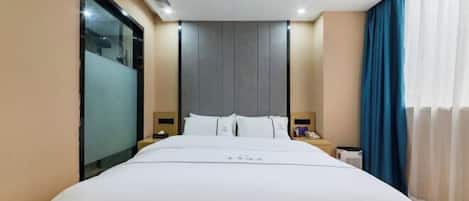 Une chambre d’hôtel avec un grand lit, une tête de lit, des tables de chevet et une fenêtre avec des rideaux.