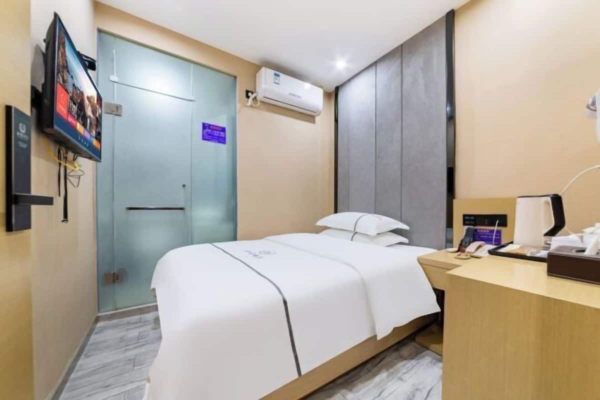 Habitación de hotel con cama, escritorio, aire acondicionado, televisor y puerta.