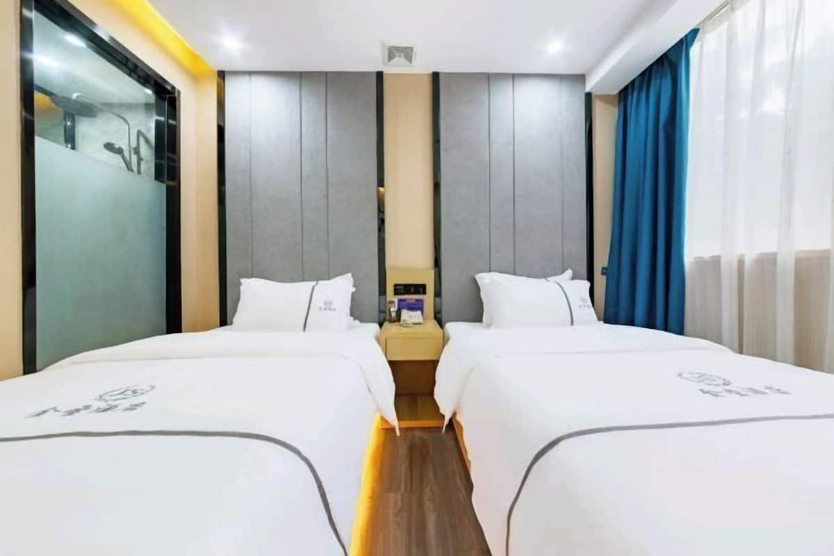 Una habitación de hotel con dos camas, una mesita de noche y un espejo.