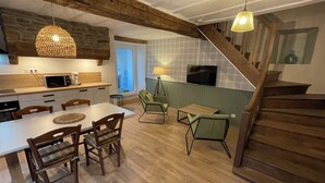 Une cuisine moderne avec un coin repas, un escalier en bois et un téléviseur.