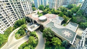 Luchtbeeld van een modern gebouwcomplex met een centrale binnentuin, omgeven door hoge woontorens.