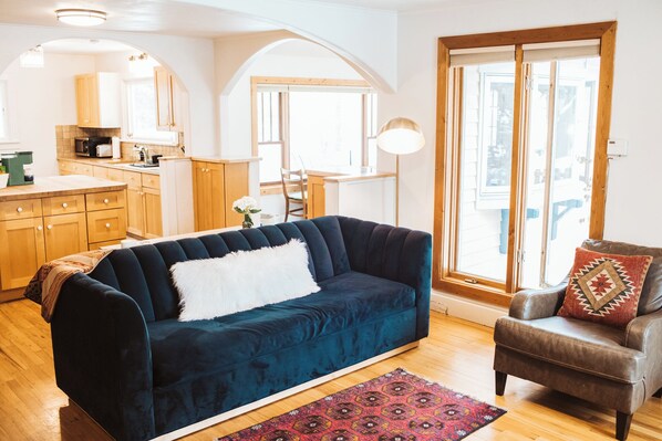 A living room with a dark blue sofa, a brown leather armchair, and a patterned rug.