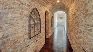 A narrow brick corridor with wooden flooring and arched doorways. - The Castle-Pool/Spa/Billiard (Henderson)