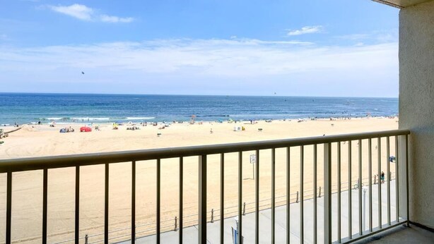 A balcony with a view of a sandy beach and the ocean. - Virginia Beach | Oceanfront Escape | Beach & Pool (Virginia Beach)