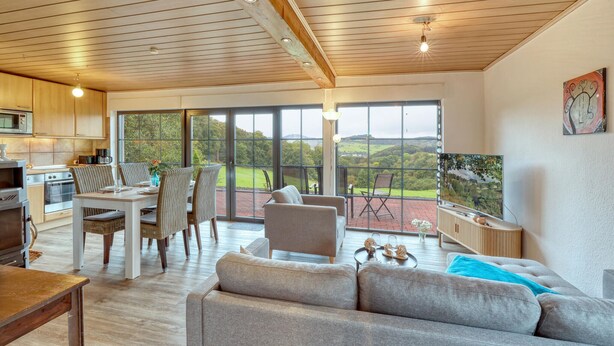 A spacious living area with a large sliding glass door leading to a balcony with a scenic view.