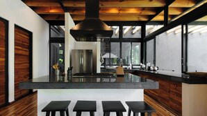 Una cucina moderna con una grande isola, sgabelli da bar e un frigorifero in acciaio inossidabile.