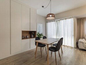 A modern dining area with a wooden table and black chairs, a pendant light, and a view of the outdoors through large windows with curtains. - Harbor & Sea View Agaete (Puerto de las Nieves)