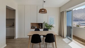 A modern dining area with a wooden table, black chairs, a hanging light fixture, and a view of mountains through a large window. - Harbor & Sea View Agaete (Puerto de las Nieves)