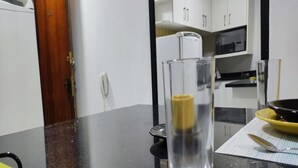 A kitchen with white cabinets, a microwave, and a black countertop. - Moderno Apartamento Centro de Curitiba (Curitiba)
