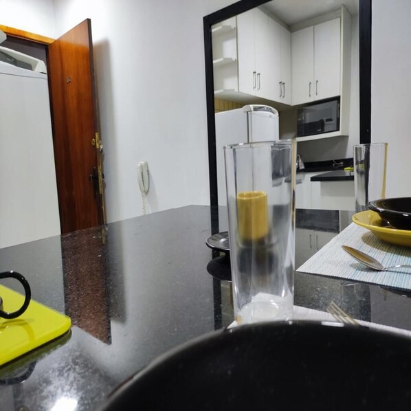 Una cucina con mobili bianchi, un forno a microonde e un piano di lavoro nero.