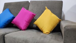 A grey sofa with three cushions in blue, pink, and yellow. - Moderno Apartamento Centro de Curitiba (Curitiba)