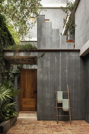 A courtyard with a wooden door, a concrete wall, and a wooden ladder leaning against it. - Suuel Hotel  Adults Only (Puerto Escondido)