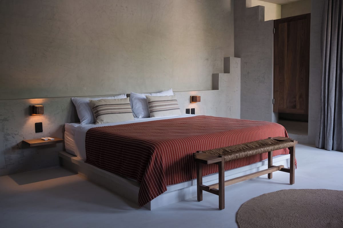 A modern bedroom with a large bed, bedside tables, and a bench.