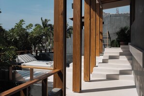 A modern outdoor seating area with a wooden deck and a staircase leading to a rooftop. - Suuel Hotel  Adults Only (Puerto Escondido)