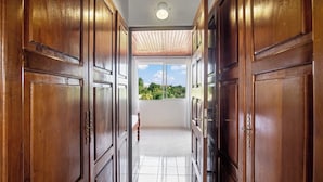 A hallway with wooden doors leading to a balcony with a view of greenery.