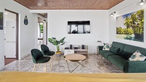 A modern living room with a green sofa, a coffee table, and a TV mounted on the wall.