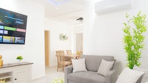 Una sala de estar moderna con un sofá gris, una mesita de centro blanca y un televisor de pantalla plana montado en la pared.