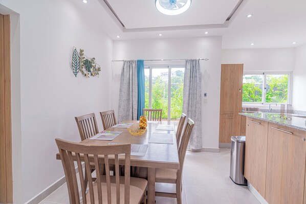 A modern kitchen with wooden cabinets, a stainless steel sink, and a dining area with a wooden table and chairs.