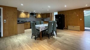 Una cocina moderna con armarios de madera, una mesa de comedor con sillas y un refrigerador negro.