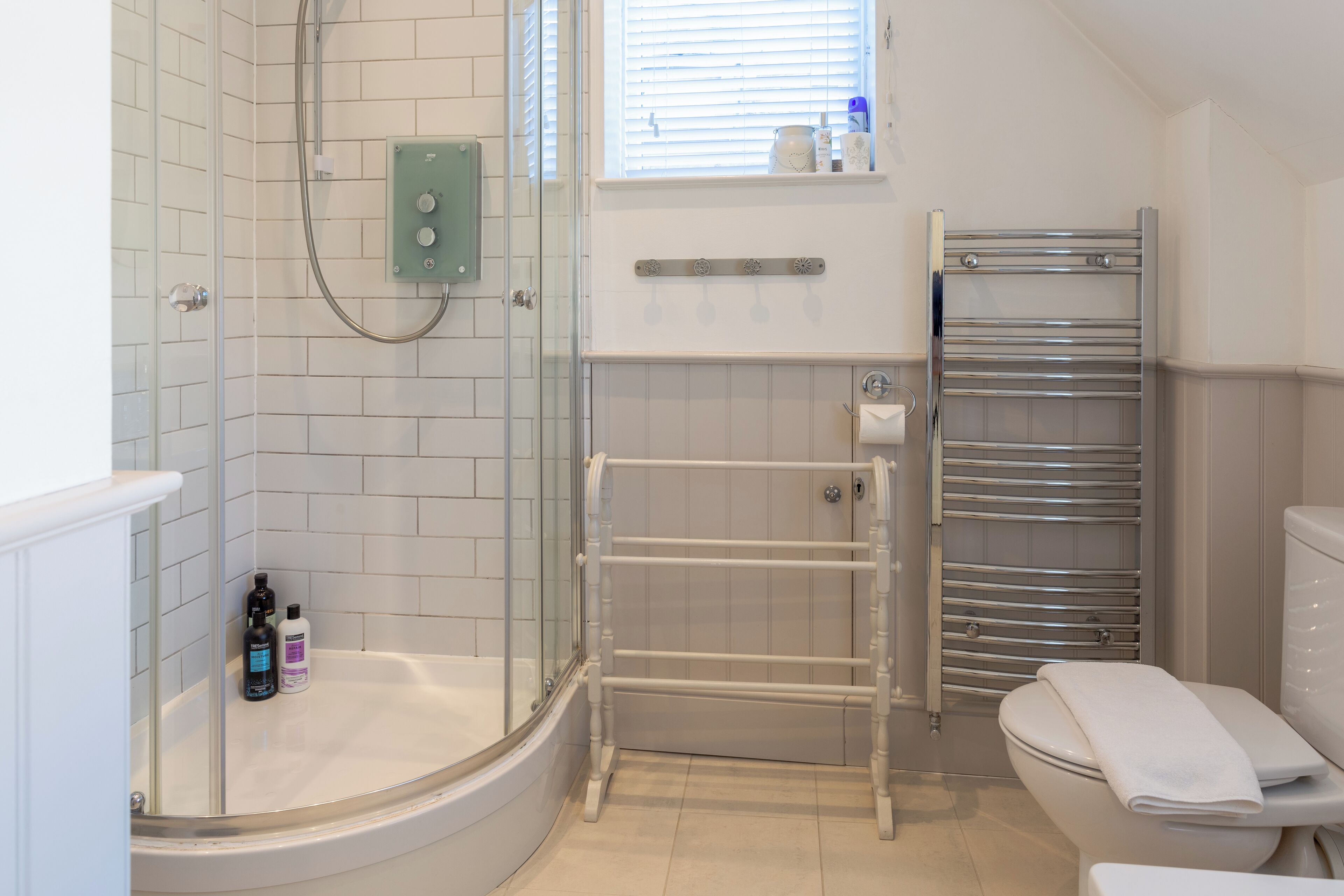 Een moderne badkamer met een douchecabine van glas, een witte badkuip, een toilet met een handdoek en een handdoekhouder.