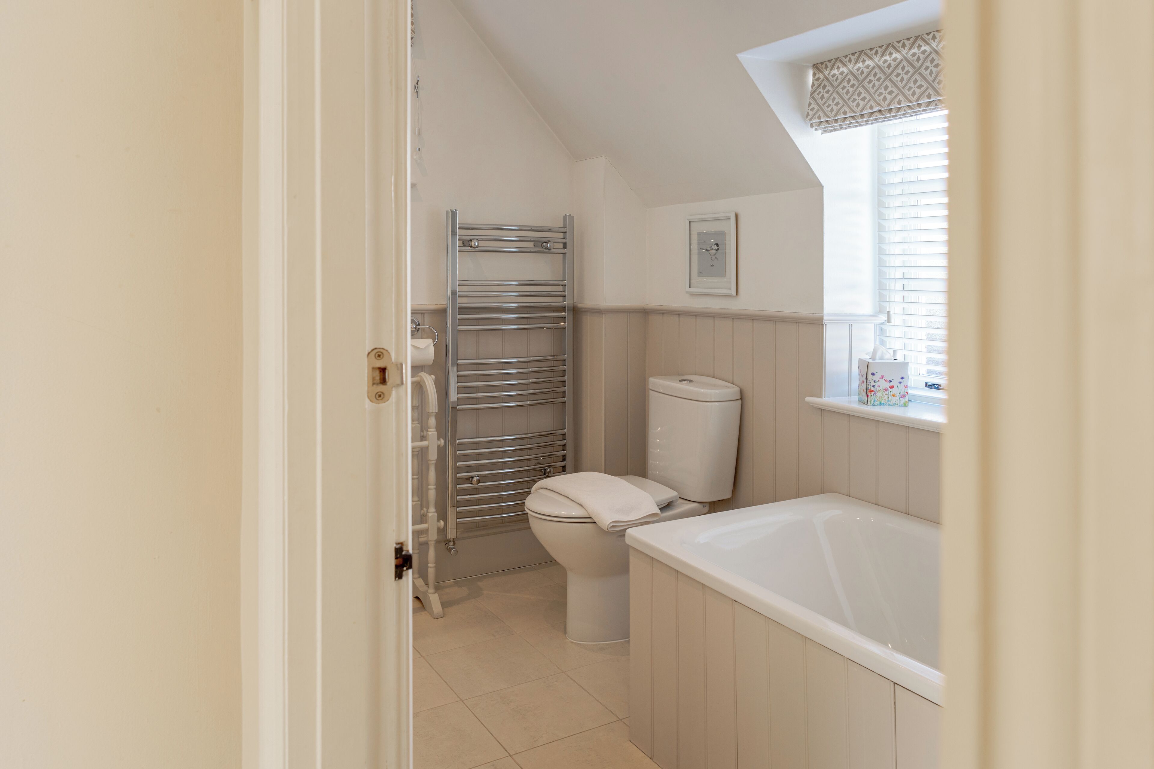 Een badkamer met toilet, handdoekhouder en een bad.
