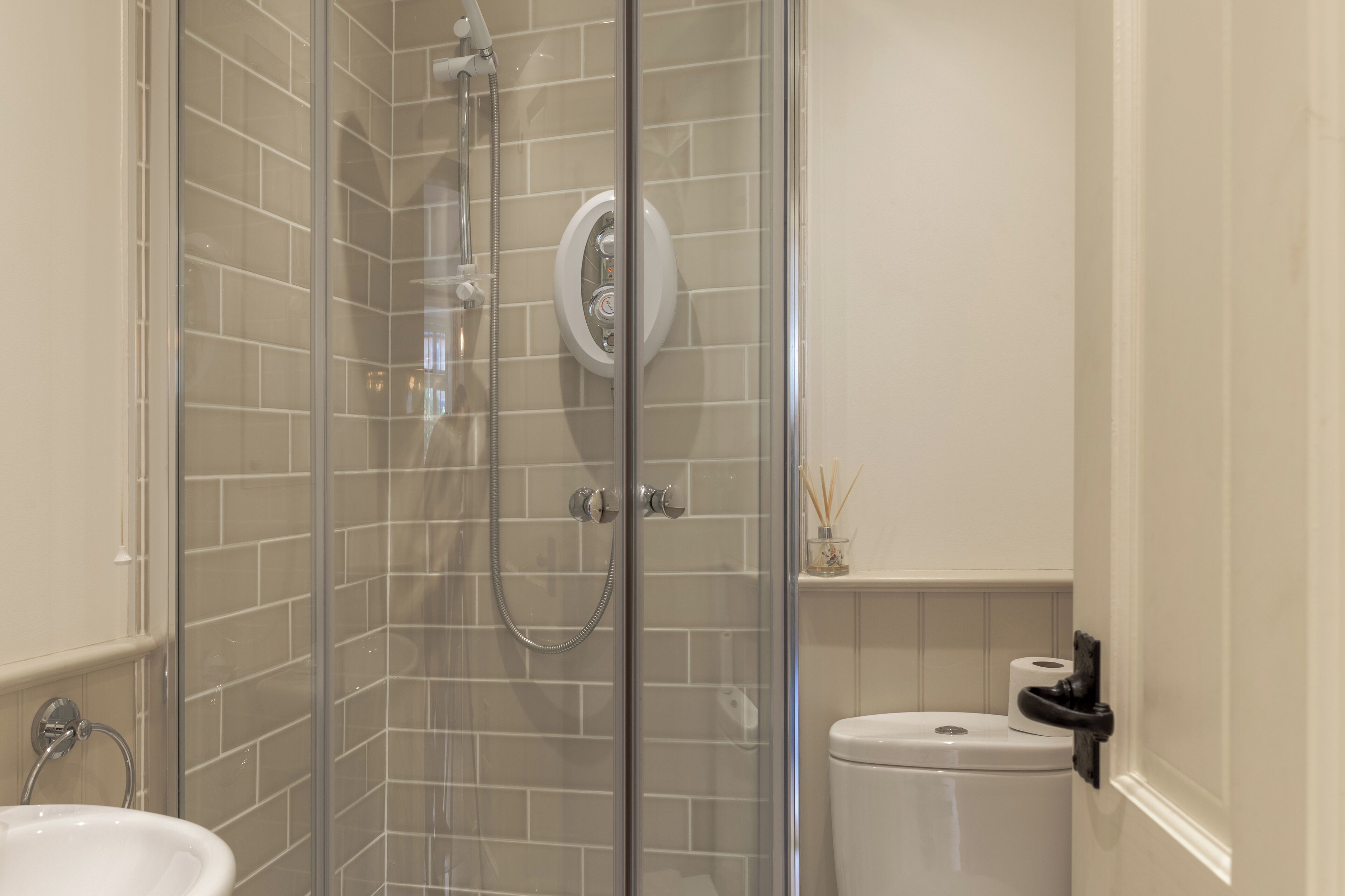 A modern bathroom with a glass-enclosed shower, a white toilet, and a sink.