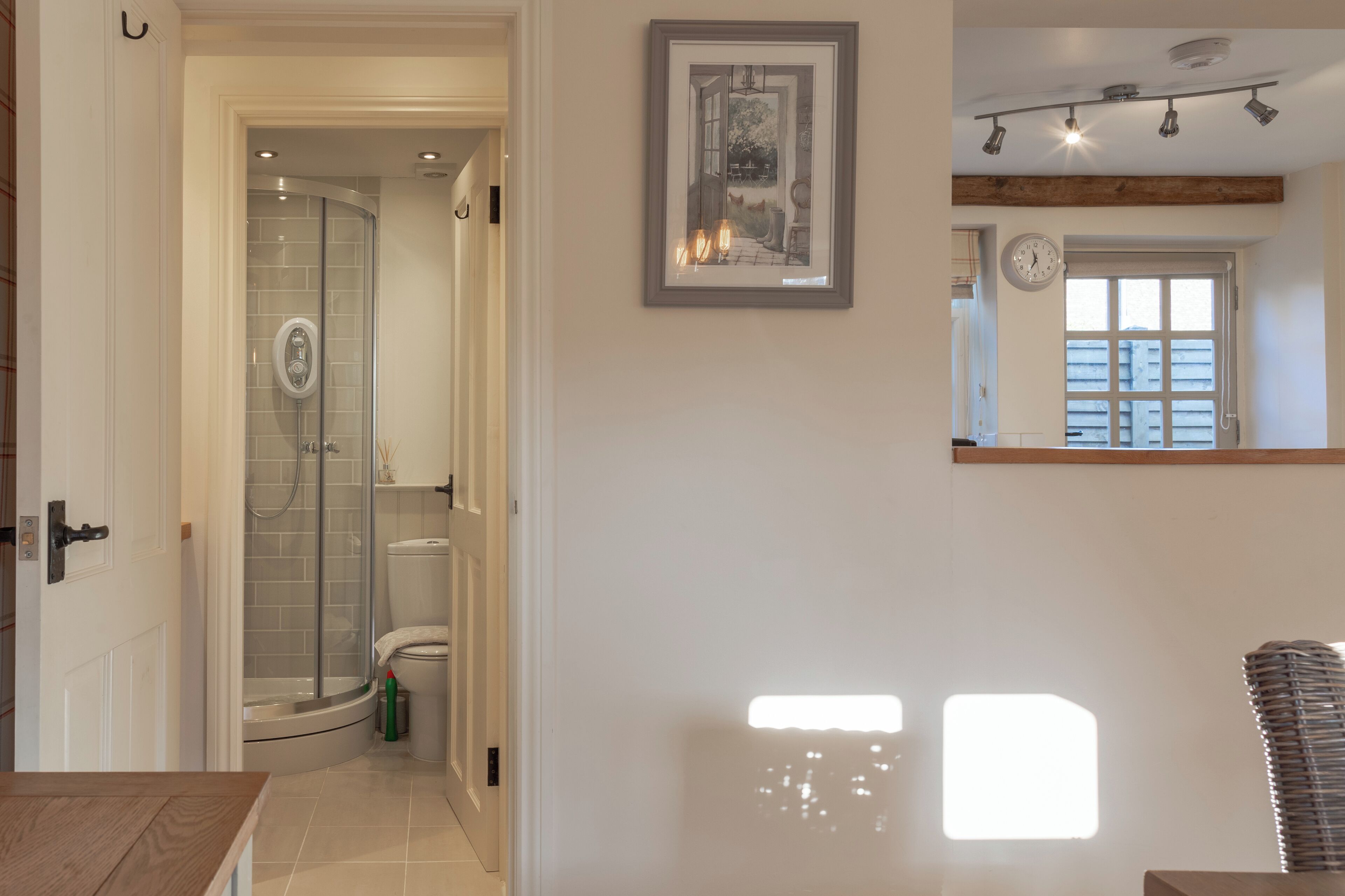A bathroom with a glass shower enclosure, a toilet, and a framed picture on the wall.