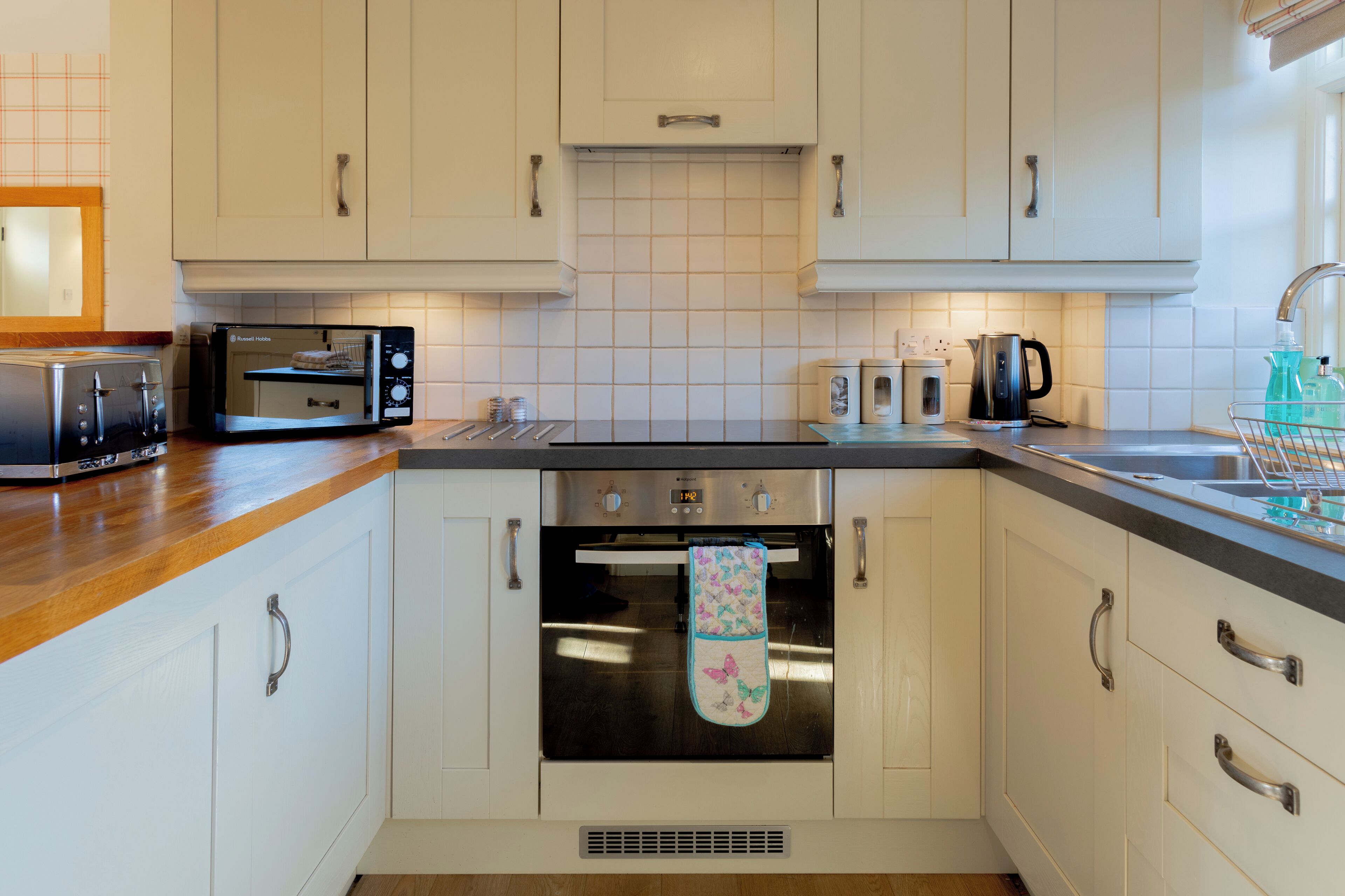 A modern kitchen with white cabinets, a stainless steel oven, a microwave, and a toaster.