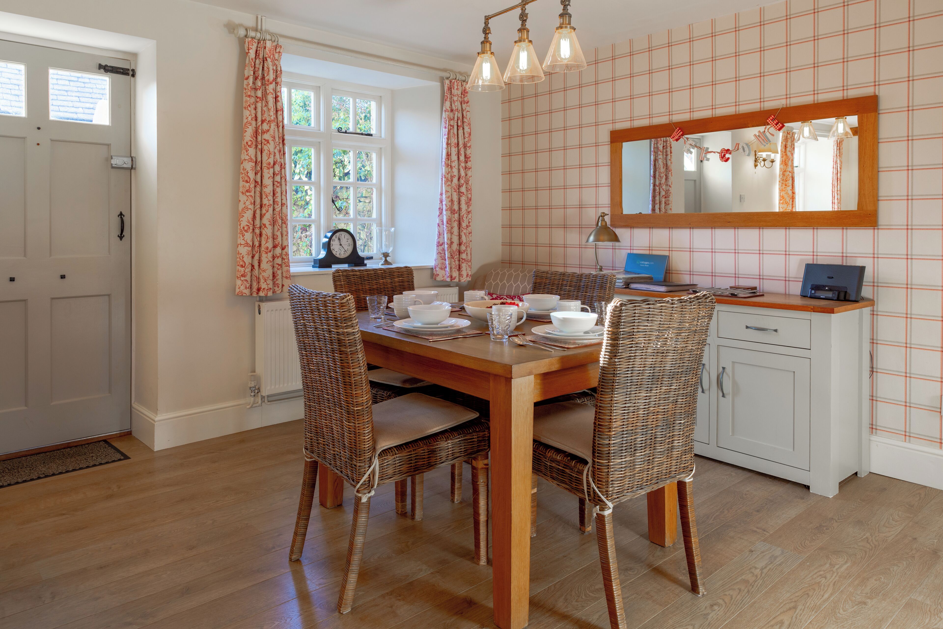 A dining area with a wooden table, wicker chairs, and a white cabinet.