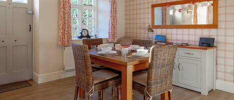 A dining area with a wooden table, wicker chairs, and a white cabinet.